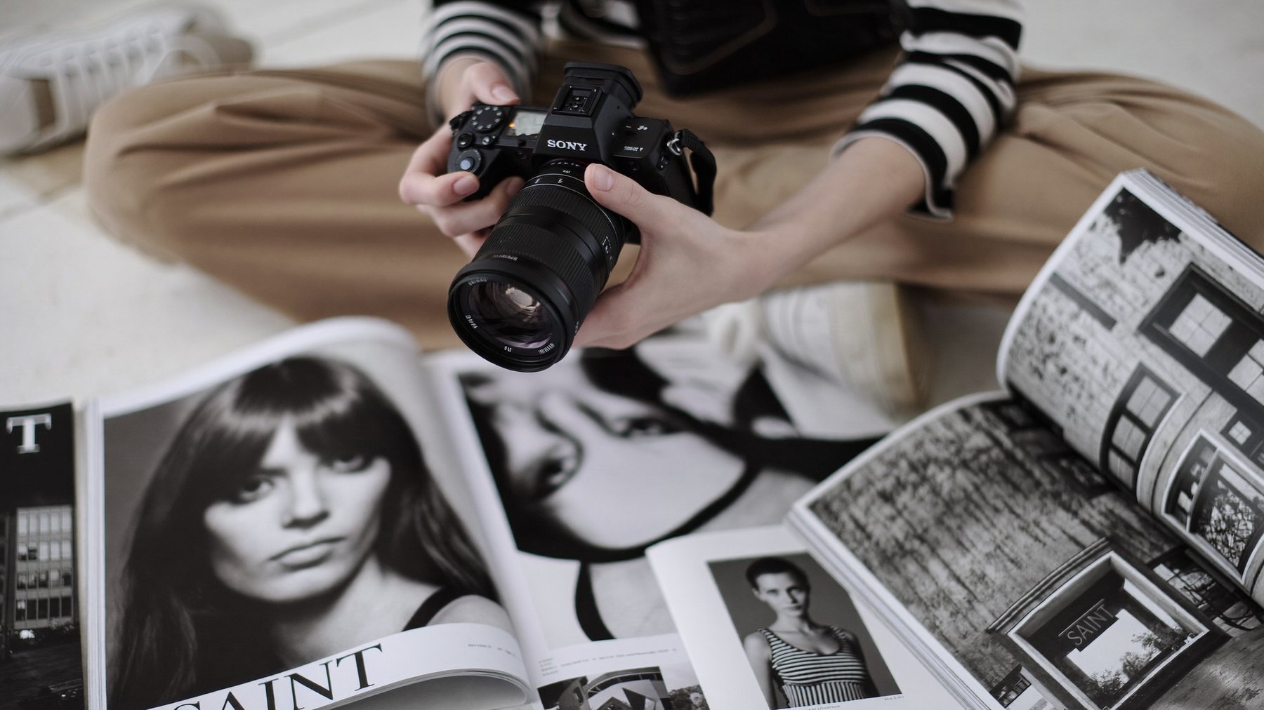 A Sony camera held over open photography magazines